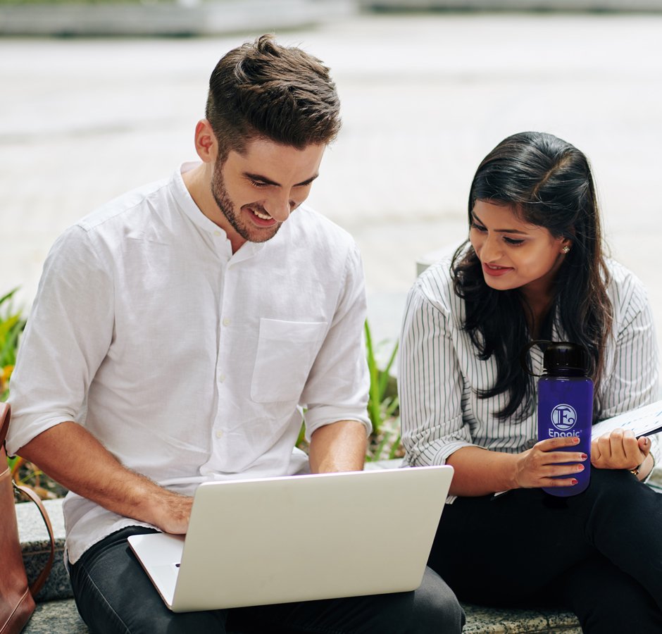 two young people smiling and looking at laptop